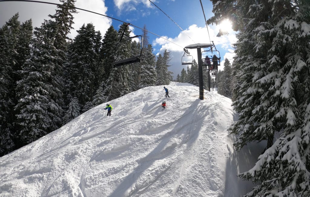 skiers on moguls under a chairlift