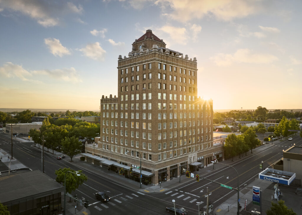 Tall brick hotel building at sunset in an urban setting.