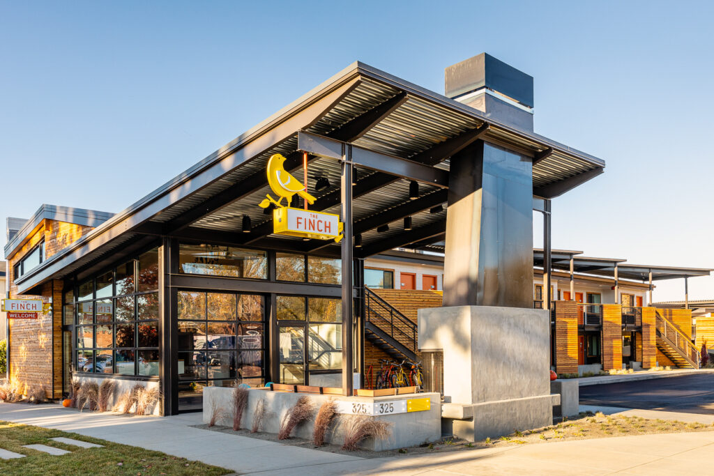 Modern exterior of The FINCH hotel with yellow bird sign and large windows.