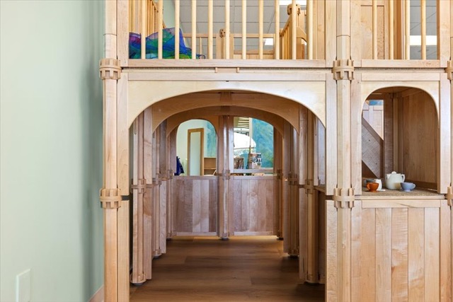 Indoor wooden play structure with archways and railings