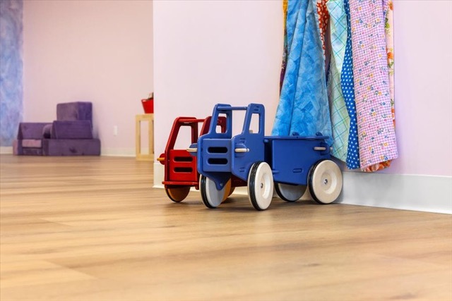 Wooden toy trucks lined up against a pink wall in a playroom