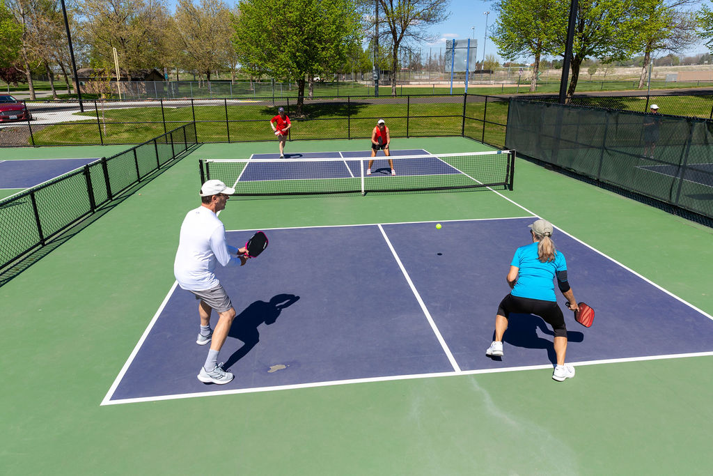 A 2v2 game of Pickleball being played on a Walla Walla court during a sunny day.
