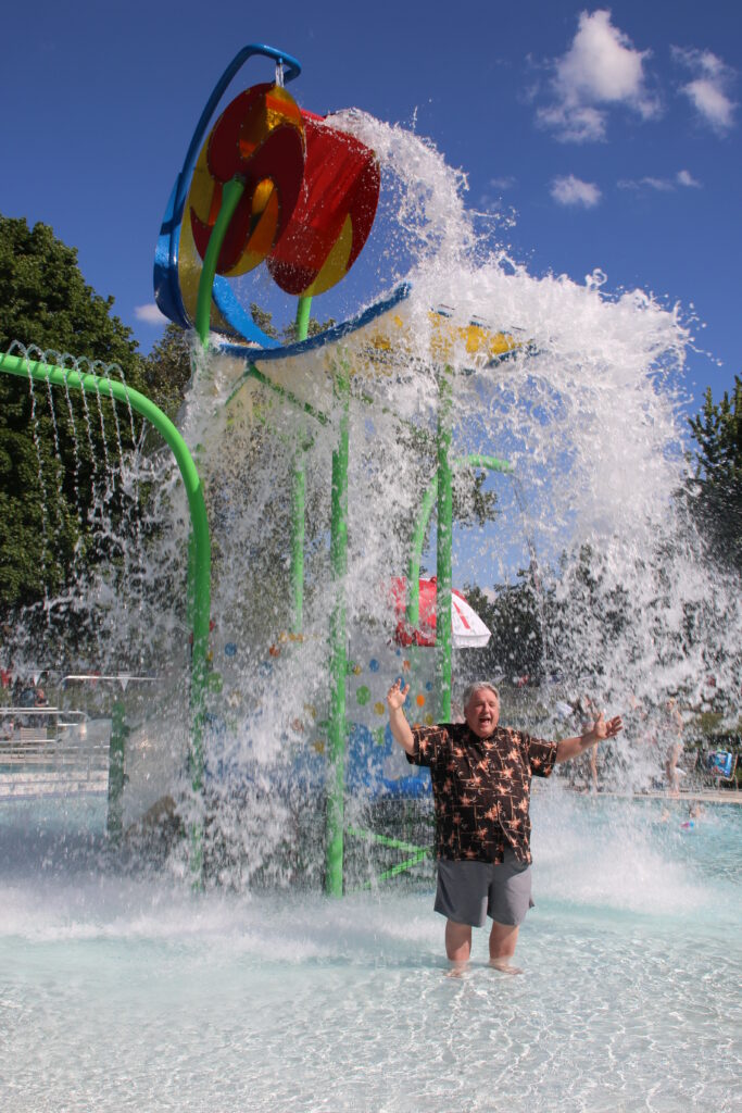 Older person getting hit by a colossal wave of water being dumped on from above.